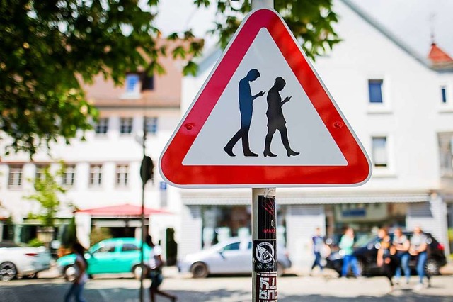 Ein Schild warn vor unaufmerksamen Smartphone-Nutzern im Straenverkehr.  | Foto: dpa