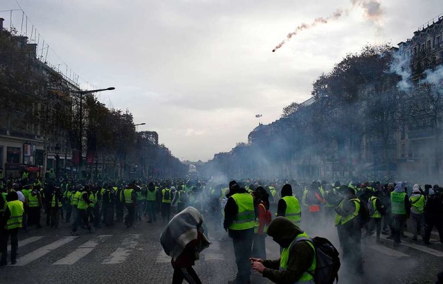 Eine Trnengaspatrone fliegt durch die...n der Gilets Jaunes (Gelbwesten) zu.  | Foto: dpa