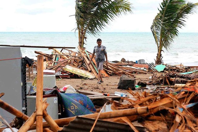 Ein Bewohner geht im indonesischen Car...ostet und schwere Schden angerichtet.  | Foto: dpa