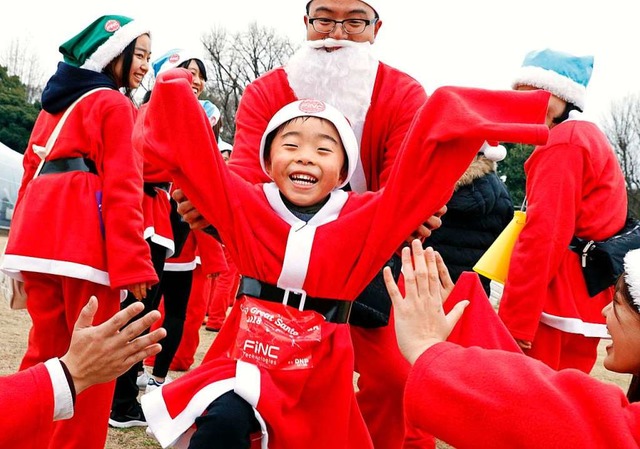 Menschen und Kinder laufen im roten Ko...im Tokyo Great Santa Charity-Lauf mit.  | Foto: dpa
