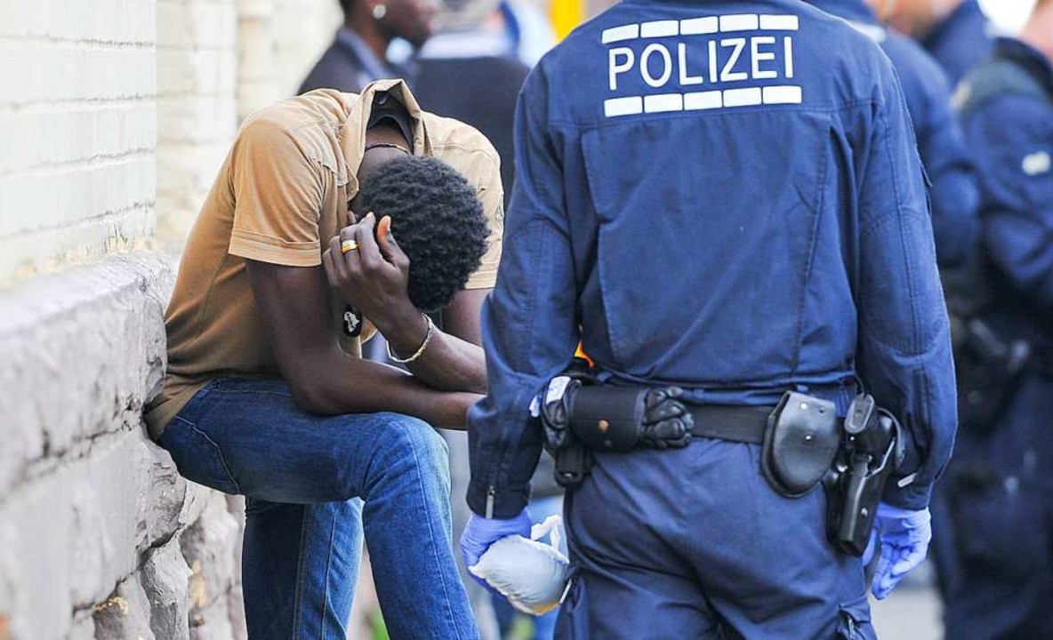 Ein Polizist berwacht bei einer Razzia einen Verdchtigen.  | Foto: dpa