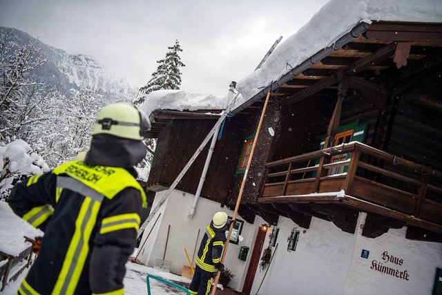 Berchtesgaden: Feuerwehrmnner rumen ein mit Schnee berladenes Dach.  | Foto: dpa