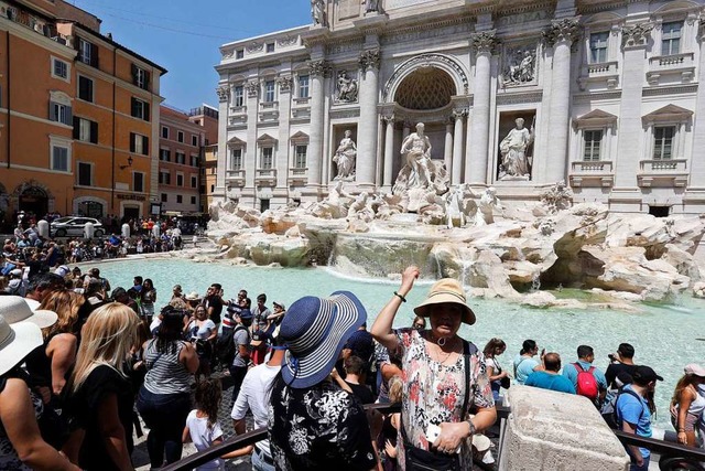 Ein Tourist wirft eine Mnze in den Trevi-Brunnen in Rom.   | Foto: dpa