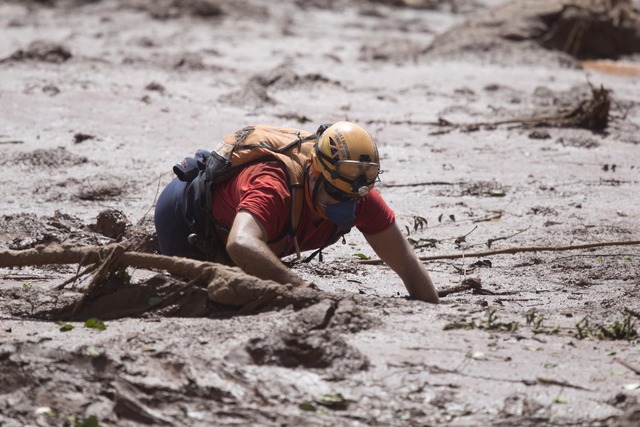 EinRettungshelfer arbeitet im Schlamm...e nach mglichen Opfer des Dammbruchs.  | Foto: dpa