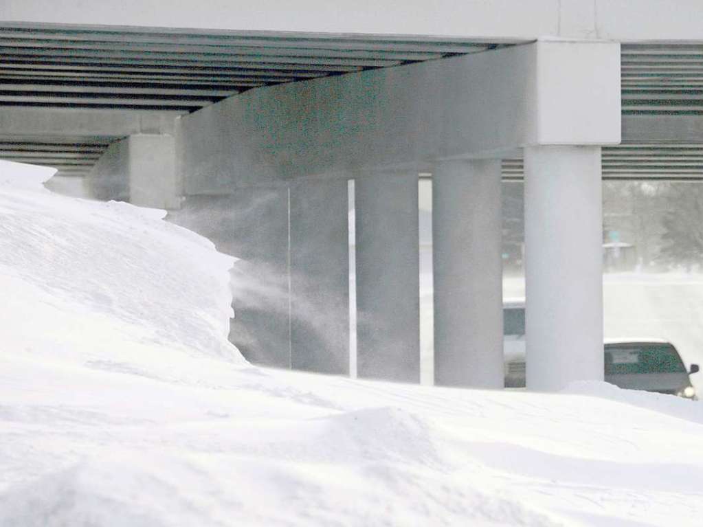 Schnee peitscht in Windben ber die Landschaft whrend Fahrzeuge eine Unterfhrung in Fargo durchqueren.