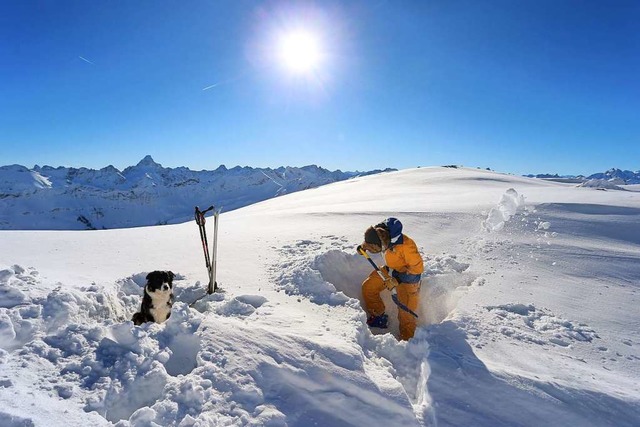 Ein Helfer grbt im Rahmen des Ausbild...im Schnee Kuhlen fr die Lawinenhunde.  | Foto: dpa