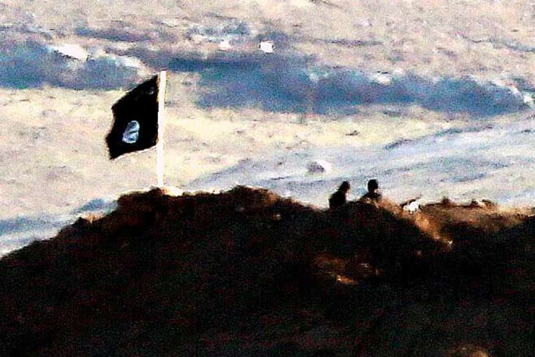 IS-Kämpfer stehen mit der Flagge des s...(IS) an der syrisch-türkischen Grenze.  | Foto: dpa