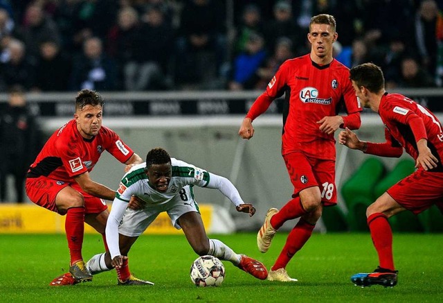 Drei gegen eins: Die Freiburger Spieler stellen Gladbachs Zakaria.  | Foto: AFP