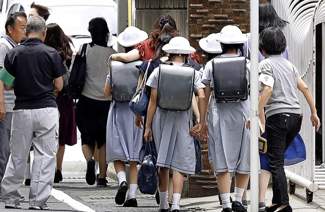 Schlerinnen verlassen mit ihren Elter...r Messerattacke ihre Schule in Tokio.   | Foto: Shinji Kita (dpa)