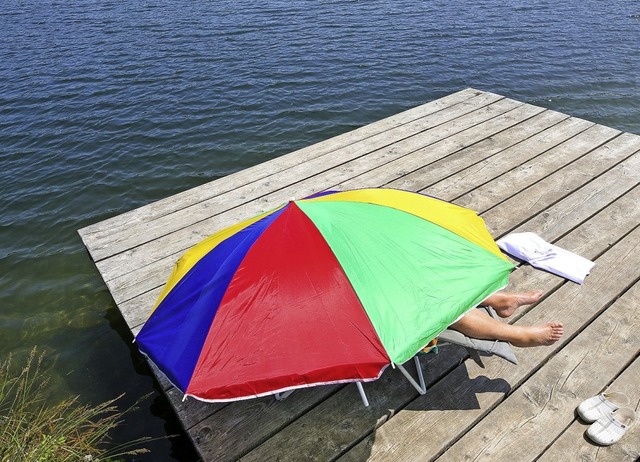 Eine Frau macht es sich an einem See gemtlich.  | Foto: Thomas Warnack (dpa)