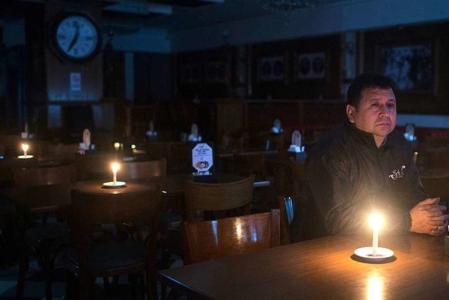Kerzenschein: Ein Mann sitzt im Dunkeln in einer Bar in Buenos Aires.  | Foto: Mario De Fina (dpa)