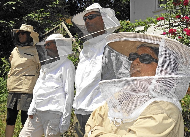 Gste im Schutzanzug verfolgen die ffnung des Bienenstockes.  | Foto: Gudrun Gehr