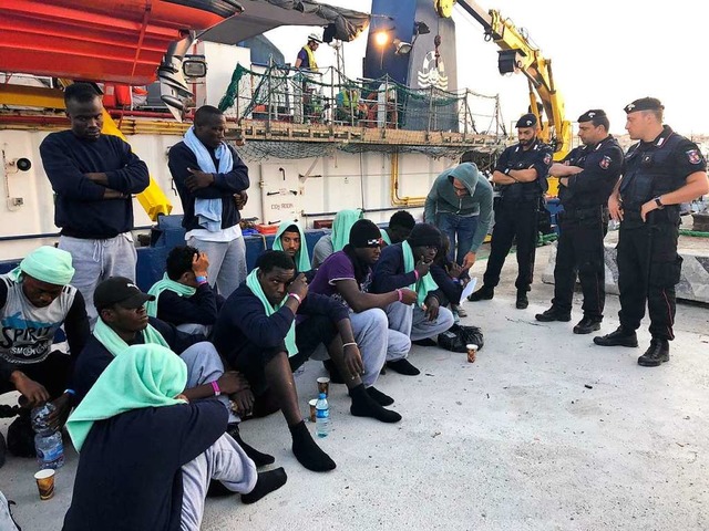 Polizisten bewachen Migranten vom Rett...f  Sea-Watch 3 im Hafen von Lampedusa.  | Foto: Annalisa Camilli (dpa)