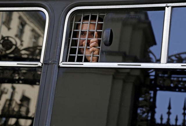 Ein festgenommener Demonstrant schaut aus dem Fenster eines Polizeibusses.  | Foto: Alexander Zemlianichenko (dpa)