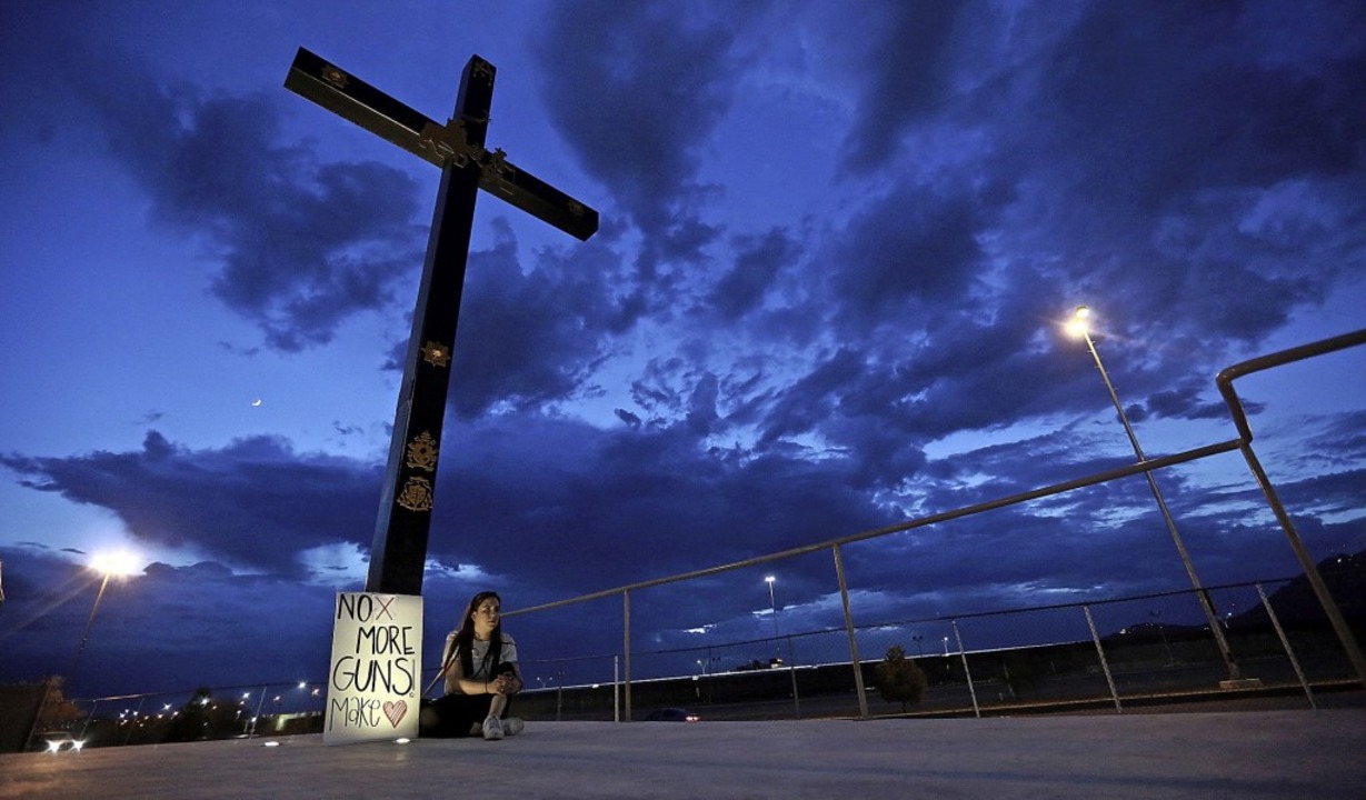 Eine Frau sitzt neben einem Schild mit... Juarez, die direkt an El Paso grenzt.  | Foto: Christian Chavez (dpa)