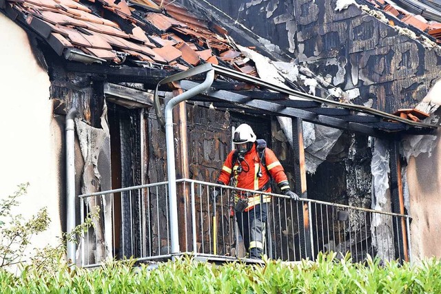 Ein Feuerwehrmann geht ber den  verbr...es Reihenhauses in der Weinbergstrae.  | Foto: Martin Eckert