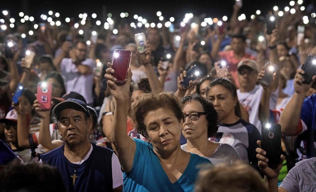 Teilnehmer einer Trauerfeier in El Paso halten statt Kerzen ihre Handys hoch.  | Foto: MARK RALSTON (AFP)