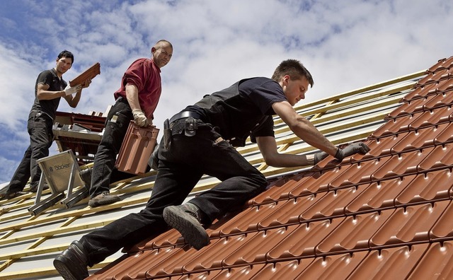Hoch oben: Auszubildender und Gesellen legen gemeinsam die Ziegel aufs Dach.   | Foto: Michael Reichel