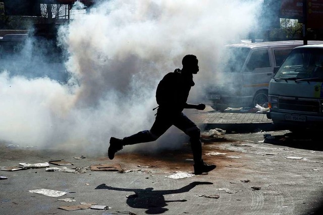 Ein Mann flchtet: Die Polizei antwort...urg mit Trnengas und Gummigeschossen.  | Foto: Themba Hadebe (dpa)