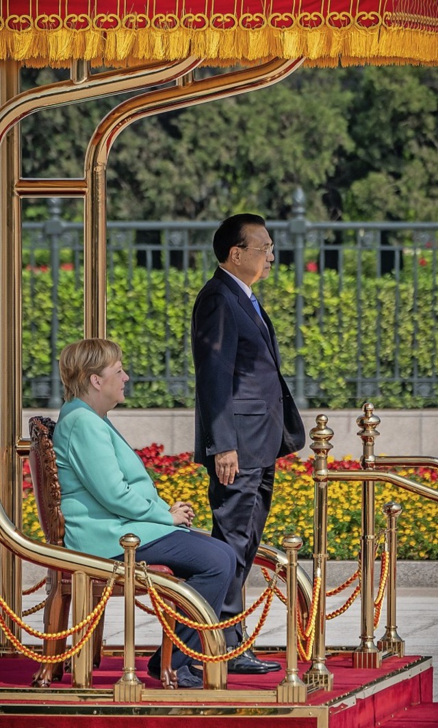 Angela Merkel lauscht der chinesischen Nationalhymne sitzend.  | Foto: Michael Kappeler (dpa)