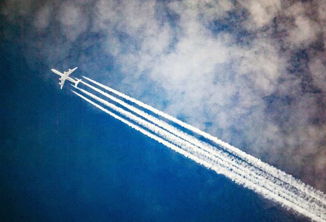 Ein Flugzeug zieht Kondensstreifen hin...r, während es durch die Wolken fliegt.  | Foto: Federico Gambarini (dpa)