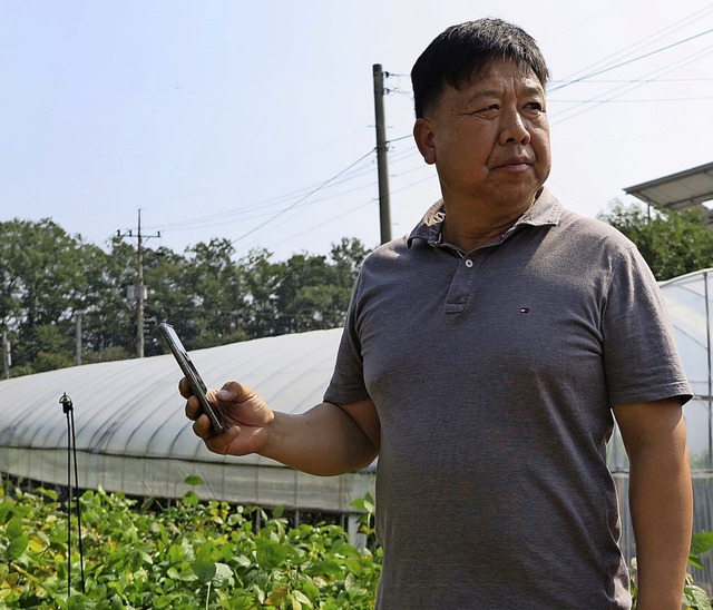 Landwirt Kim Yong Seob erklrt, wie si...system fr die Felder bedienen lsst.   | Foto: Dirk Godder (dpa)