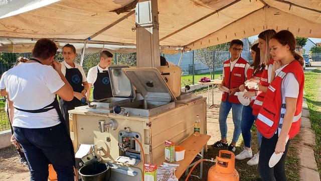 Rotkreuzfreiwillige und Kochschler arbeiten zusammen in  der  Feldkche.  | Foto: DRK-Kreisverband Emmendingen