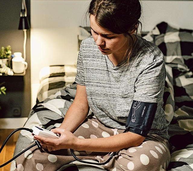 Eine Frau misst abends ihren Blutdruck.  | Foto: Elizaveta - stock.adobe.com