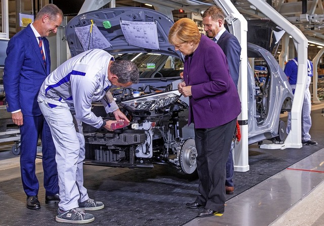 Kanzlerin Angela Merkel   mit VW-Konze...band fr die Montage des Elektroautos.  | Foto: Jens Bttner (dpa)