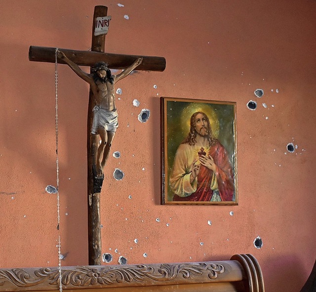Einschusslcher neben Kruzifix und Bildnis von Jesus Christus  | Foto: Gerardo Sanchez (dpa)