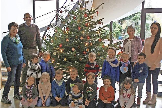 Kindergartenkinder schmücken Weihnachtsbaum
