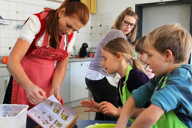 Birgit Wenz erklrt den Kindern die Handhabung des Becherkchen-Kochbuchs.  | Foto: Erich Krieger