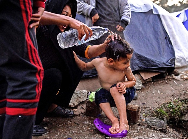 Die Zustnde in den berfllten Flcht...anische Mutter ihren Sohn mit Wasser.   | Foto: ARIS MESSINIS (AFP)