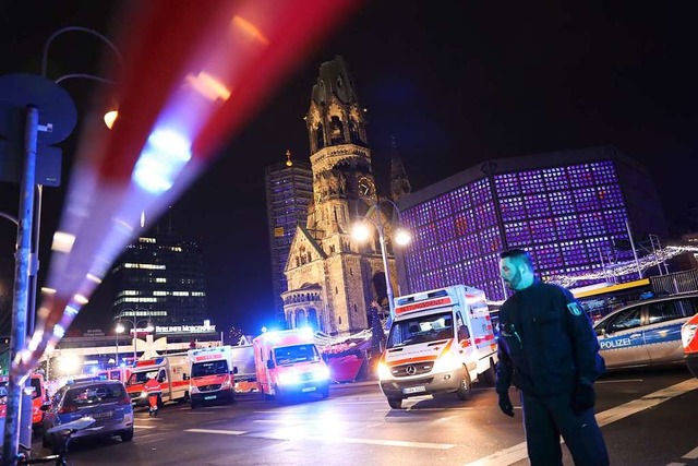 Polizisten und Rettungskrfte stehen v...m Lastwagen ber den Platz gerast war.  | Foto: Michael Kappeler (dpa)