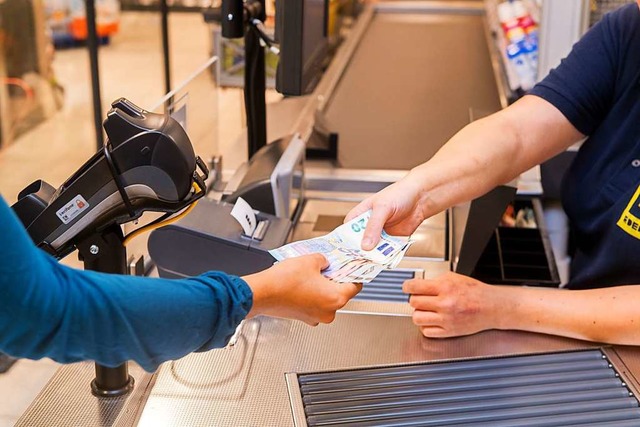 In einem Supermarkt hebt eine Kundin beim Bezahlen auch gleich Bargeld ab.  | Foto: Benjamin Nolte (dpa)