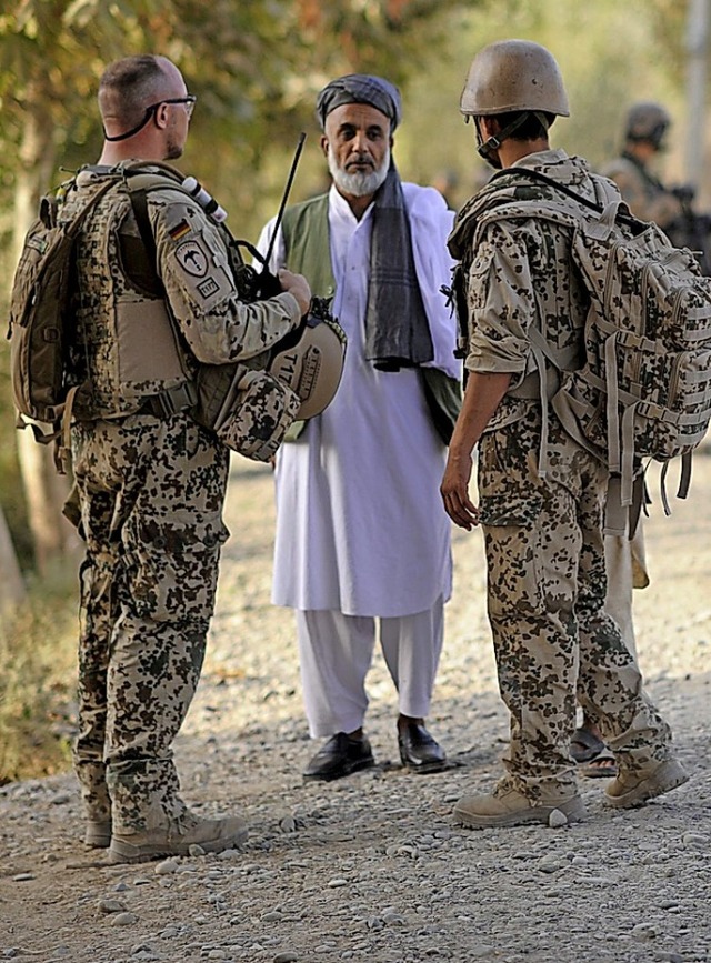 Ein Bundeswehrsoldat (l.) und ein Dolm...) sprechen nahe Kundus mit einem Mann.  | Foto: Maurizio Gambarini