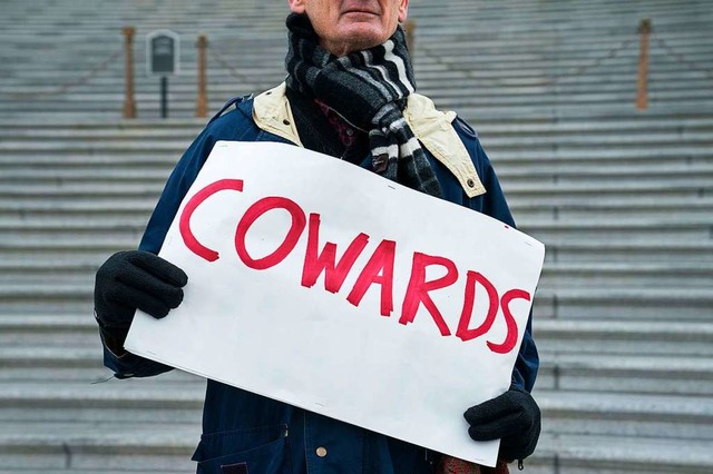Cowards, Feiglinge: Mit dem Plakat zielt ein Demonstrant auf die US-Senatoren.  | Foto: Sarah Silbiger (AFP)