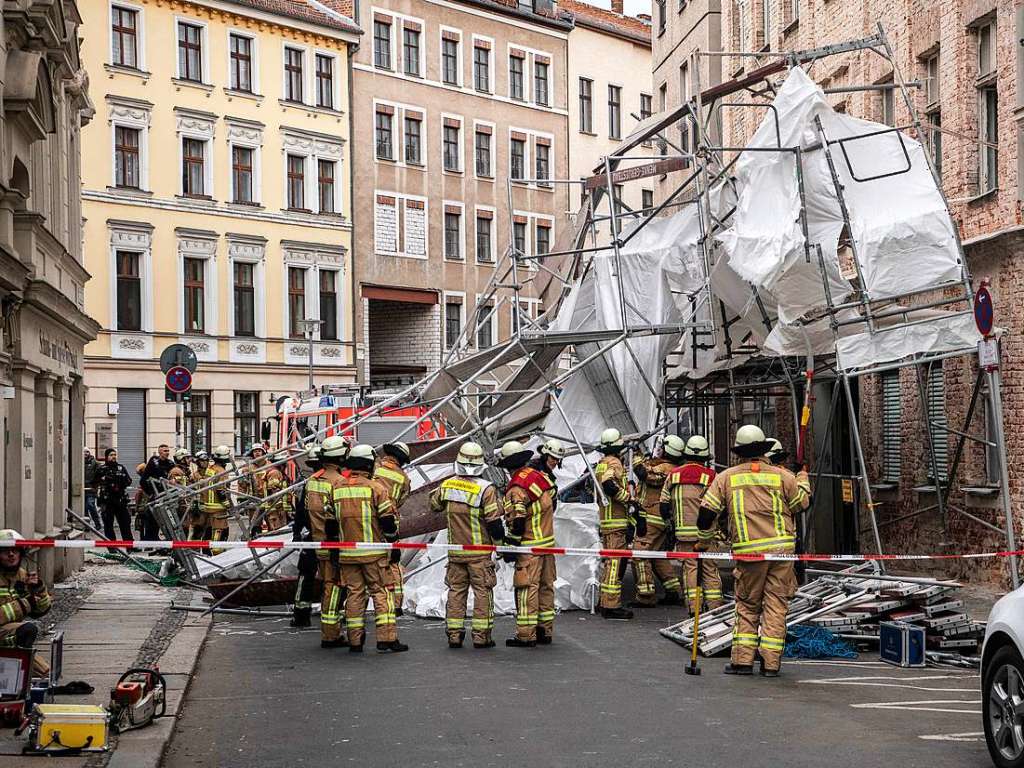 Feuerwehrleute stehen in Berlin in der Sophienstrae an einem von Windben eingestrzten Gerst.