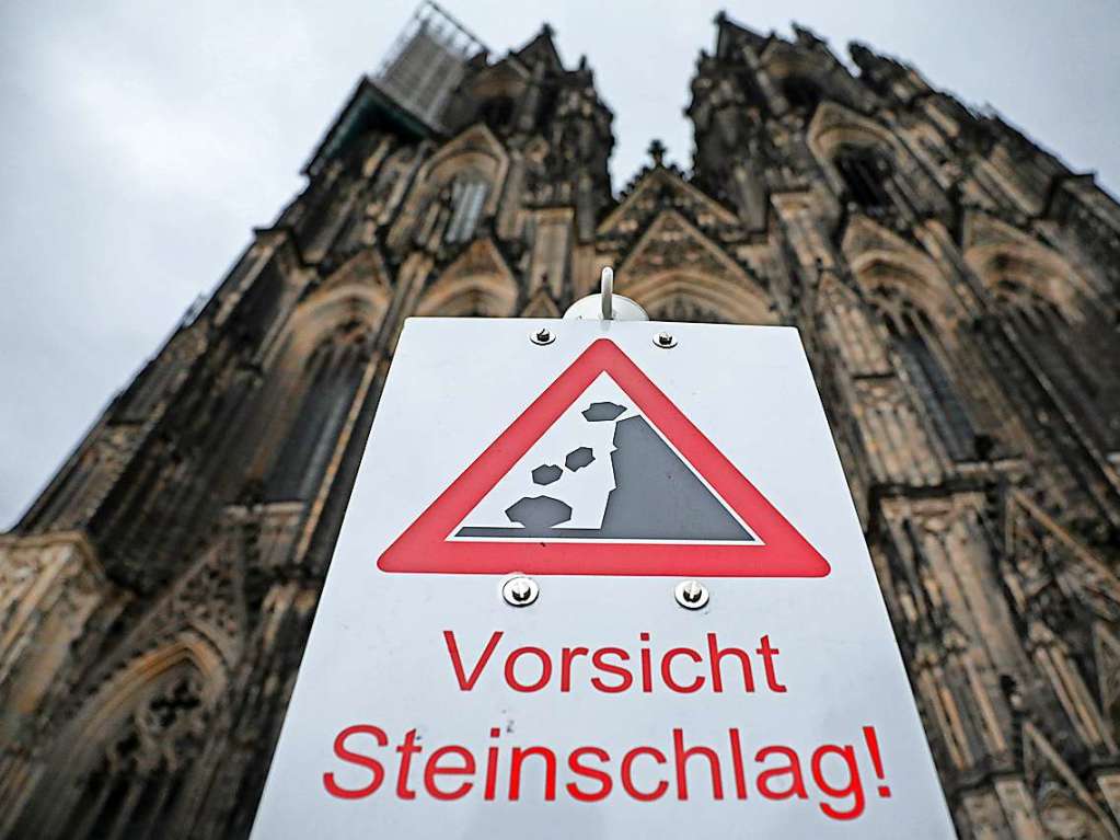 Ein Schild „Vorsicht Steinschlag“ steht vor dem Klner Dom.