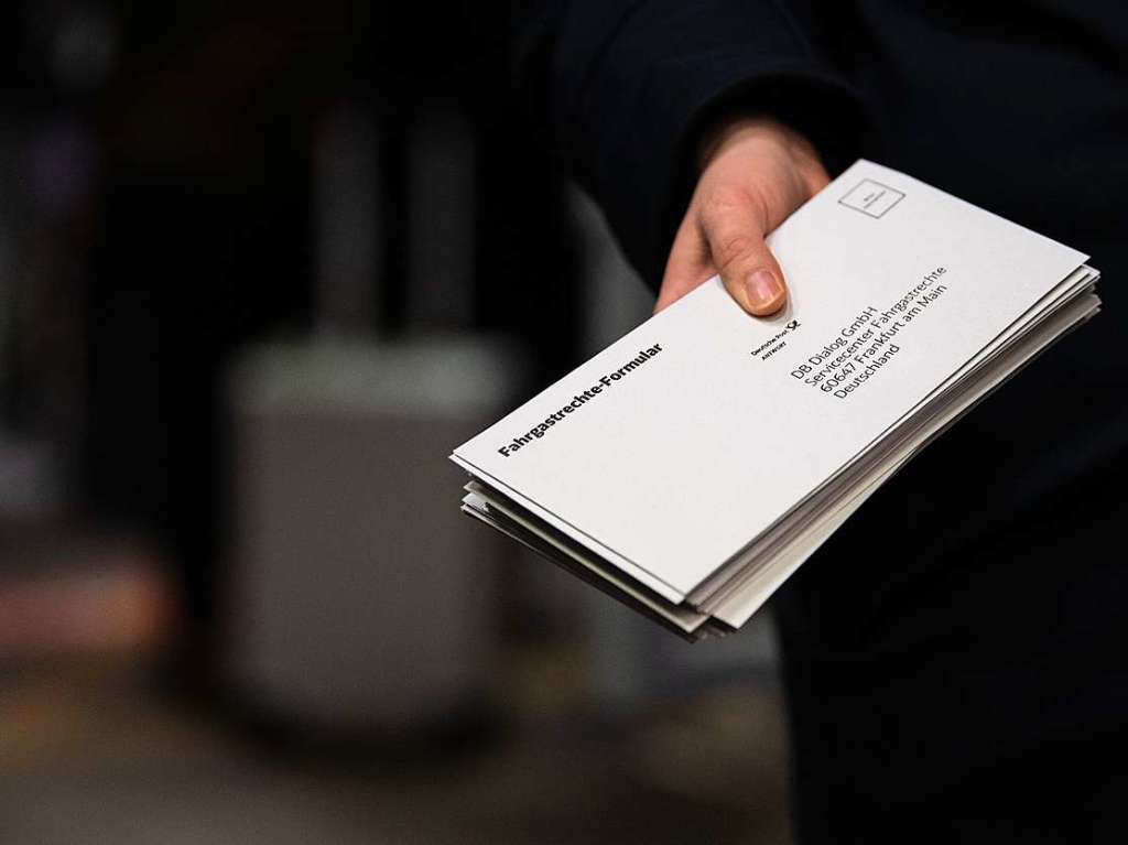 Eine Mitarbeiterin der Bahn hat im Stuttgarter Hauptbahnhof Fahrgastrechte-Formulare in der Hand.