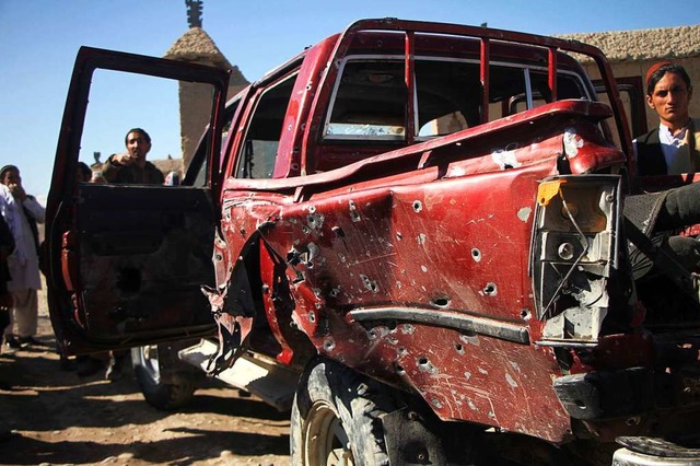 Bewohner stehen neben einem von Kugeln durchlchertem Fahrzeug.  | Foto: Saifurahman Safi (dpa)