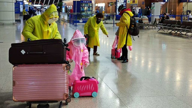 Menschen in Schutz-Regencapes und mit Mundschutz am Flughafen in Schanghai  | Foto: Klaus Gabriel