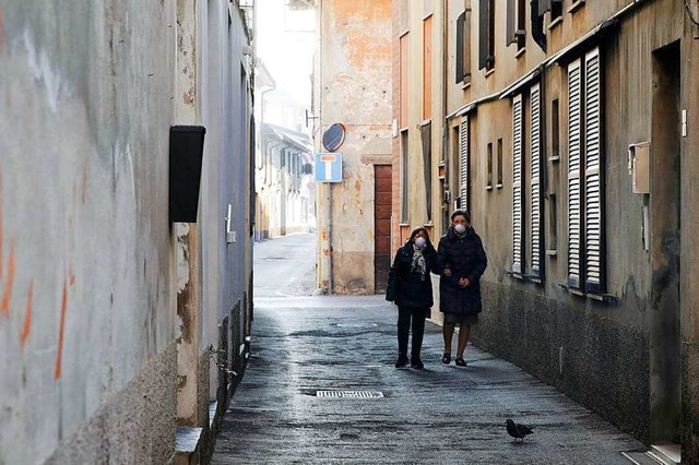 Zwei Frauen gehen mit Mundschutz durch...Gasse der italienischen Stadt Codogno.  | Foto: Luca Bruno (dpa)