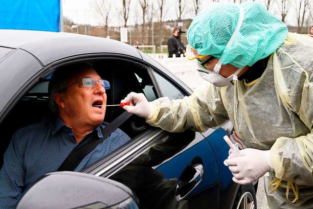 rzte und Helfer in Schutzkleidung neh... am Wagen einen Abstrich fr den Test.  | Foto: THOMAS KIENZLE (AFP)
