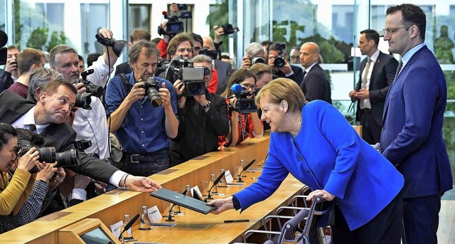 Letzte Informationen: Angela Merkel be...ister Jens Spahn eine Mappe gereicht.   | Foto: TOBIAS SCHWARZ (AFP)