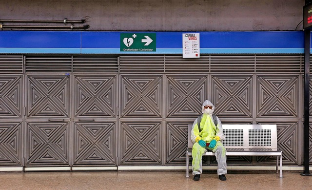 Ein Mann in Schutzkleidung sitzt in einer U-Bahnstation in Madrid.  | Foto: Guillermo Santos (dpa)