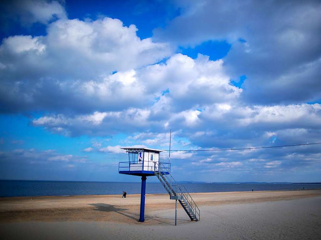 Ahlbeck: Nur wenige Urlauber sind am Strand neben der Seebrcke an der Ostsee unterwegs.