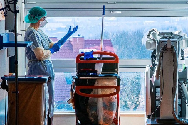 Eine Mitarbeiterin legt auf einer Isol...bevor sie ein Patientenzimmer betritt.  | Foto: Jens Bttner (dpa)