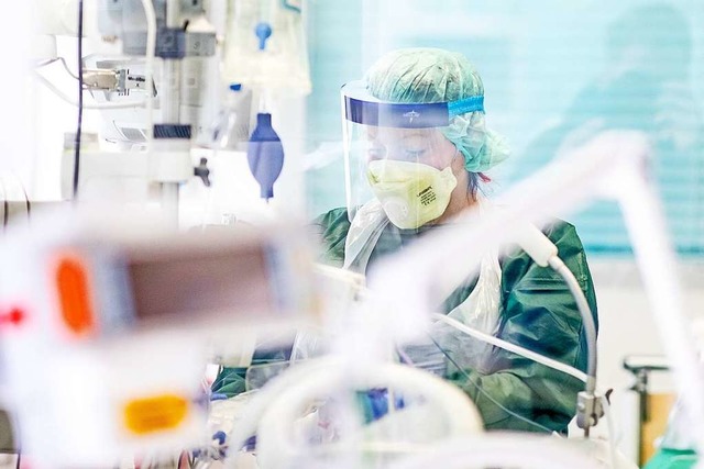 Krankenpfleger arbeiten in Schutzkleid...ntensivstation des Uniklinikums Essen.  | Foto: Marcel Kusch (dpa)