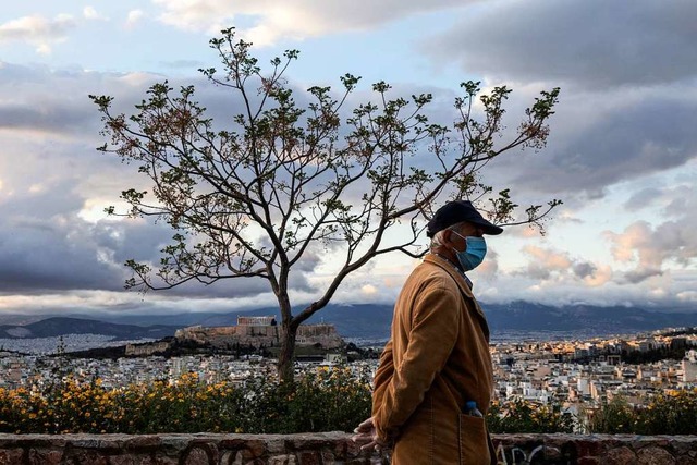 Athen: Ein Mann mit Mundschutz spazier... Akropolis-Hgels und der Stadt Athen.  | Foto: Petros Giannakouris (dpa)